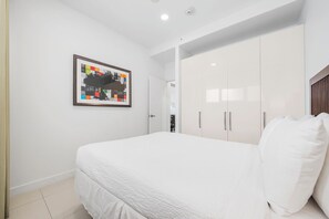 Een slaapkamer met een bed, een witte inbouwkast en een ingelijste foto aan de muur.