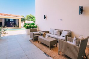 An outdoor seating area with wicker furniture, a coffee table, and a potted plant. - Spacious 2BR Condo w/ Free Parking near Palm Beach (Noord)