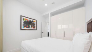A bedroom with a bed, white walls, a framed picture, and a wardrobe. - Spacious 2BR Condo w/ Free Parking near Palm Beach (Noord)