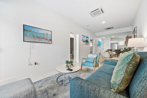 A modern living room with a sofa, a coffee table, and a painting of flamingos on the wall.