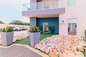 A modern building with a reception area, potted plants, and a landscaped entrance.