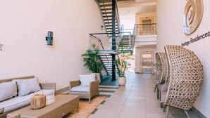 A spacious lobby with a staircase, wicker furniture, and potted plants. - 2BR Condo! Resort-Style Pool! (Noord)