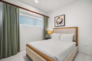 A hotel room with a bed, curtains, a window, a wall-mounted artwork, and a bedside lamp. - Poolside Bliss: 2-Bedroom Condo with Patio Noord (Noord)