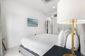Ein modernes Hotelzimmer mit einem großen Bett, einem Nachttisch, einer Lampe und einem Bild an der Wand.