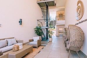 A modern interior with a staircase, wicker furniture, and a sign for Heritage Residences. - Poolside Bliss: 2-Bedroom Condo with Patio Noord (Noord)