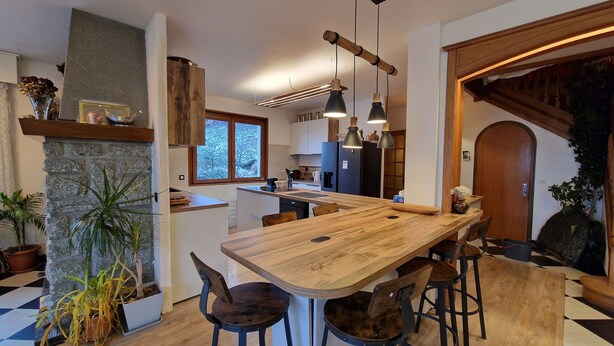 A modern kitchen with a wooden dining table, bar stools, and pendant lights. - Guy and Rose's cottage (Passy)