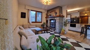 A living room with a sofa, a fireplace, and a checkered floor. - Guy and Rose's cottage (Passy)
