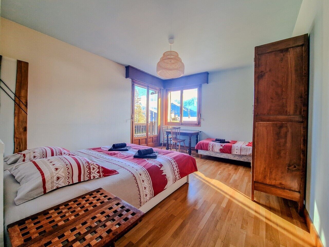 Un dormitorio con dos camas, piso de madera, un escritorio y ventana con vistas.