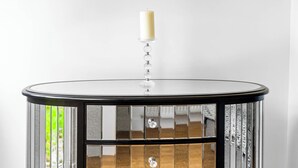 Una mesa redonda con diseño negro y de cristal, que incluye un candelabro en la parte superior.