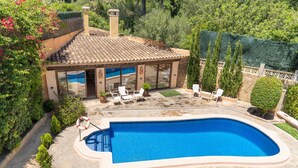 A swimming pool with a tiled deck, surrounded by potted plants and a covered patio area with outdoor seating. - El Ranchito, villa in Paguera, Majorca, quiet area, with swimming pool and barbecue. (Peguera)