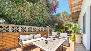 An outdoor patio with a sofa, chairs, and a table. There is a brick wall and a wooden fence. - El Ranchito, villa in Paguera, Majorca, quiet area, with swimming pool and barbecue. (Peguera)