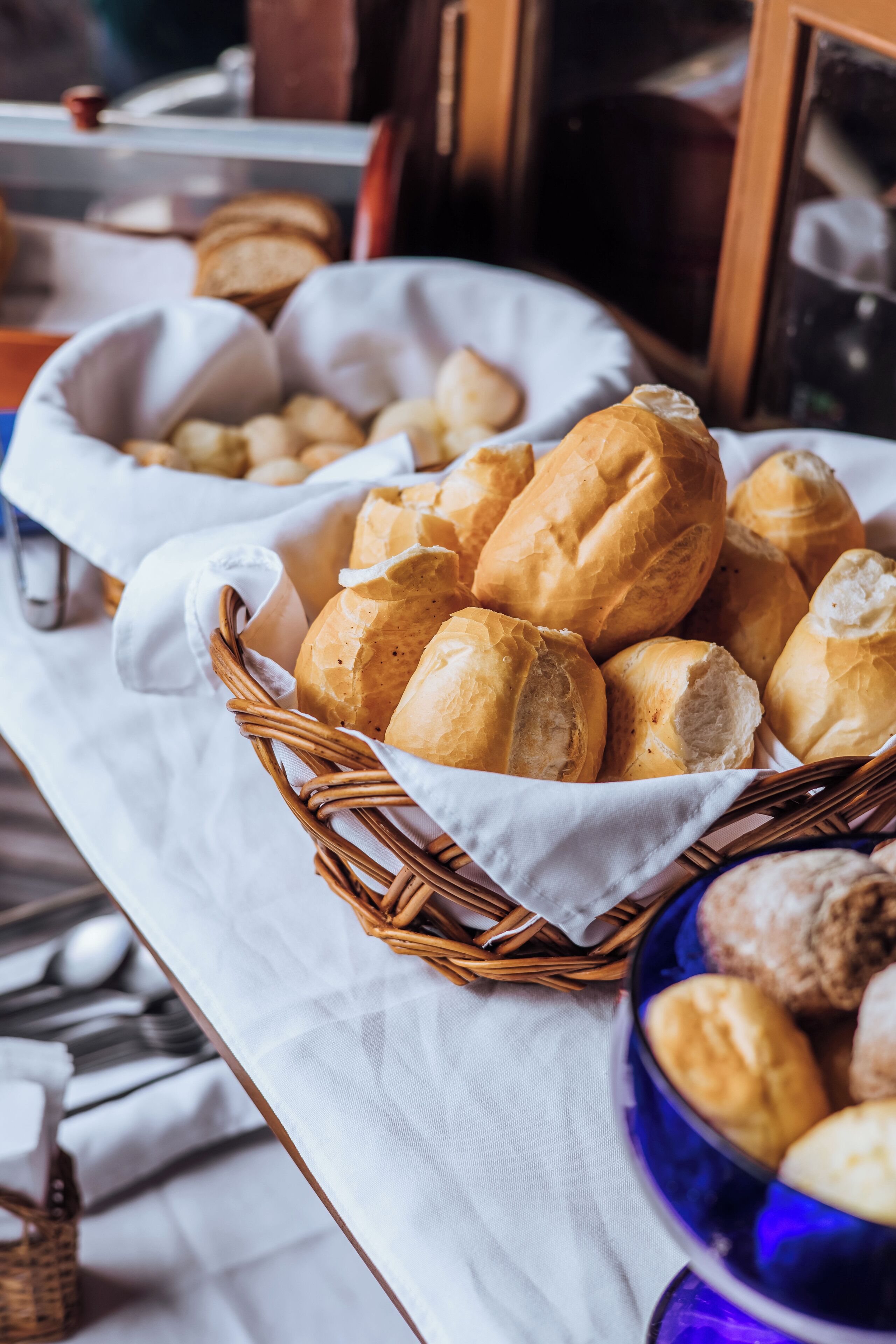 A basket of bread on a table with a white cloth.