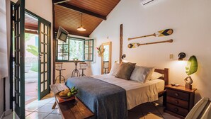 A bedroom with a bed, bedside table, and a window with a view of the outdoors. - Pousada Vila das Pedras (Ilhabela)
