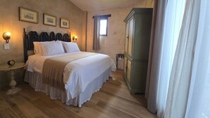 A bedroom with a bed, a nightstand, a cabinet, and framed pictures on the wall. - Loft Pienza 6 (Val'Quirico)