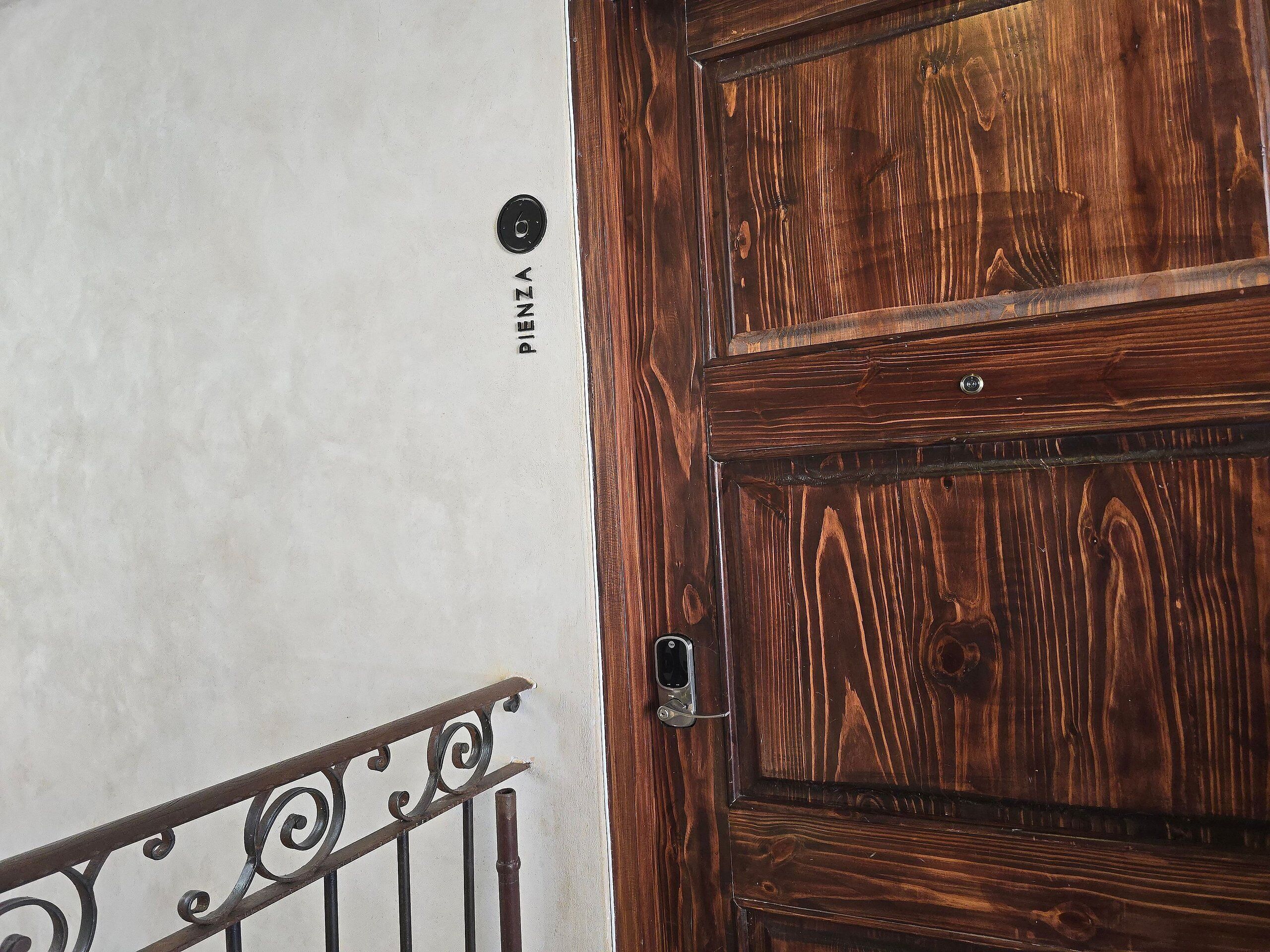 A wooden door with a metal handle and a metal railing with decorative elements.