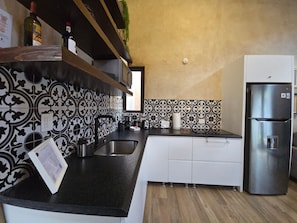 Una cocina moderna con salpicadero estampado, electrodomésticos de acero inoxidable y muebles de cocina blancos.