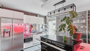 A modern kitchen with stainless steel appliances, a black countertop, and a potted plant.