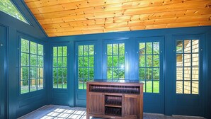 Una habitación con techo de madera, ventanas amplias y un armario de madera.