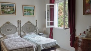 A bedroom with two single beds, a dresser, a window with red curtains, and two framed paintings on the wall. - Villa Torre Blanca in Farinole (Farinole)