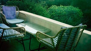 A balcony with wicker chairs and a table, overlooking a lush green landscape and a sunset. - Villa Torre Blanca in Farinole (Farinole)