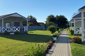 A residential area with a paved pathway, a lawn, and a small garden with flowers.