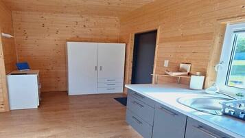 A compact kitchen with wooden walls, a white refrigerator, a sink, and a window.