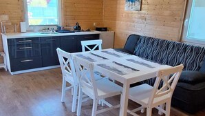 Puisesti sisustettu tila, jossa on ruokapöytä ja tuolit, sohva sekä keittiöalue.
