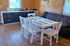 Un interior de madera con una mesa de comedor y sillas, un sofá y una zona de cocina.