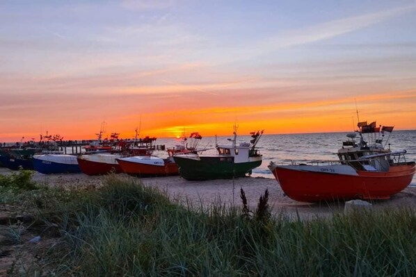 A row of boats docked at a pier during sunset.