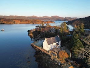 A house by a lake with a view of mountains in the background. - As Shown On Tv Island Hideaway (Gairloch)