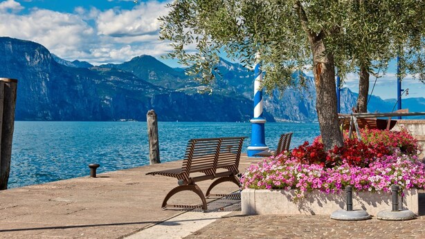 A bench by a waterfront with a mountain backdrop. - Al Porticciolo Apartment (Castelletto)