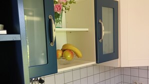 A kitchen with a blue cabinet containing a fruit bowl with bananas and apples, a stainless steel sink, and a bottle of beer on the counter. - Alexa, the cozy bright vacation apartment in Überlingen, 10 minutes walk to the lake (Überlingen)