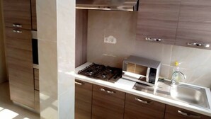Cozinha moderna com fogão a gás, micro-ondas e pia de aço inoxidável.