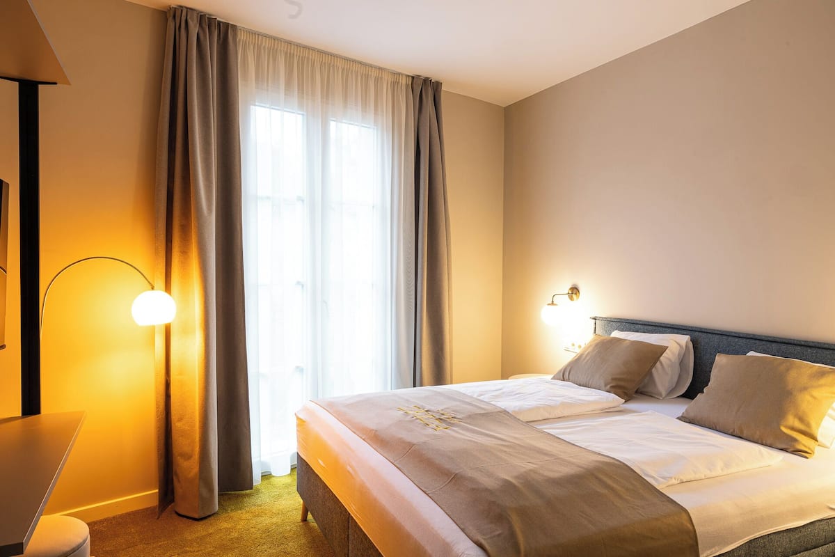 A hotel room with a bed, a desk, and a lamp.