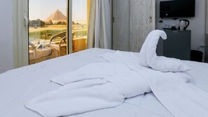 Une chambre d’hôtel avec un lit, une télévision et une vue sur les pyramides.