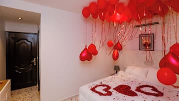 A bedroom with a bed, a door, and red balloons.