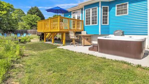 A backyard with a wooden deck, outdoor seating, and a hot tub. - Heated Pool King Bed Jacuzzi Bath Arcade (Winston-Salem)