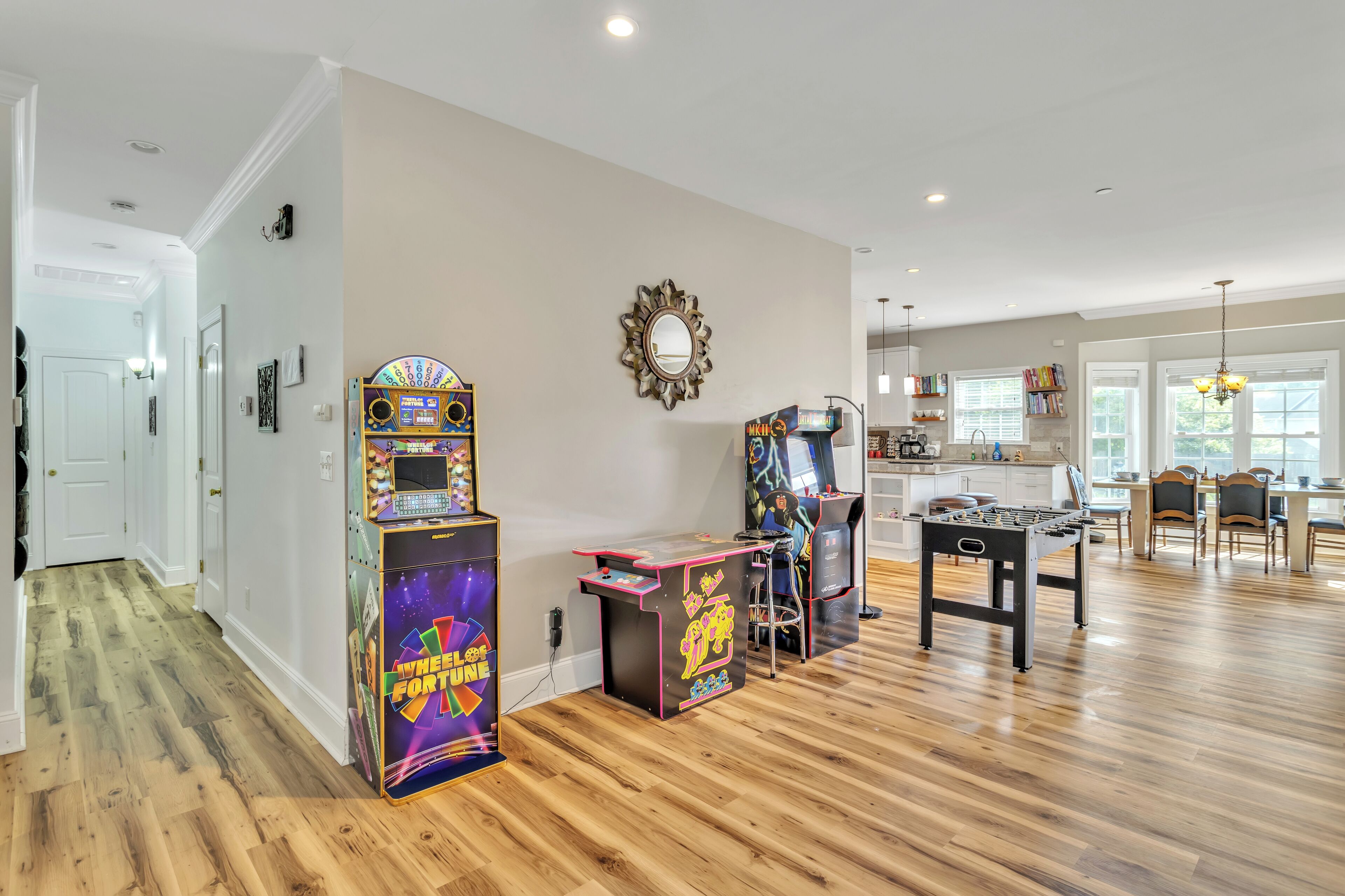 A spacious living area with a wooden floor, a foosball table, and arcade games.