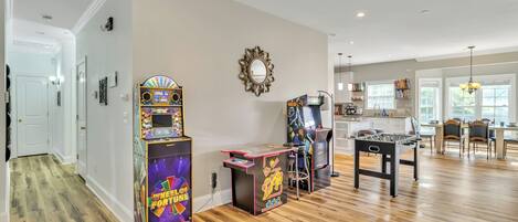 A spacious living area with a wooden floor, a foosball table, and arcade games.