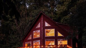 A large, two-story wooden cabin with multiple windows and a balcony, surrounded by trees. - Wilderness Ridge | Private Cabin w/ Mountain Views (Linden)