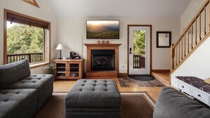 A living room with a fireplace, a sofa, a coffee table, and a staircase. - Wilderness Ridge | Private Cabin w/ Mountain Views (Linden)