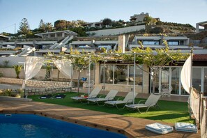 Relax by the pool surrounded by a hillside view and shaded by a pergola.