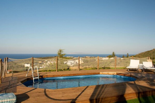 Relax by the ocean-view pool surrounded by lounge chairs and a wooden deck.