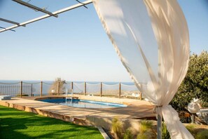 Enjoy a serene poolside retreat with ocean views from the comfort of a deck.