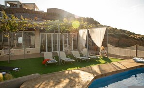 Relax by the pool surrounded by a serene landscape view.