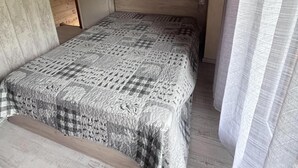 Ett sovrum med ett träpanelat tak, en säng med ett mönstrat överkast och en hängande lampa.