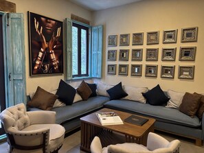 Una sala de estar con un sofá modular, sillones, una mesa de centro y un cartel grande en la pared.