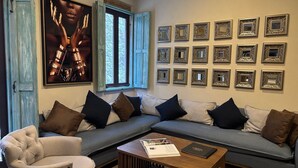 A living room with a sectional sofa, armchairs, a coffee table, and a large poster on the wall. - Castello di Carlo – Loft Carlo II. (Val'Quirico)