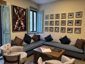 Una sala de estar con un sofá modular, sillones, una mesa de centro y un cartel grande en la pared.