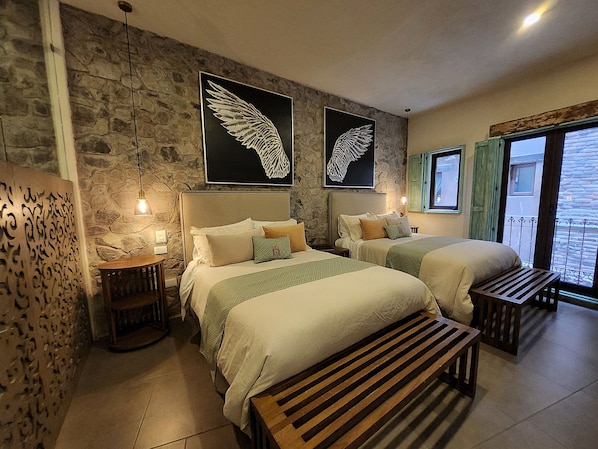 Habitación de hotel con dos camas, una pared de piedra y una obra de arte con alas.